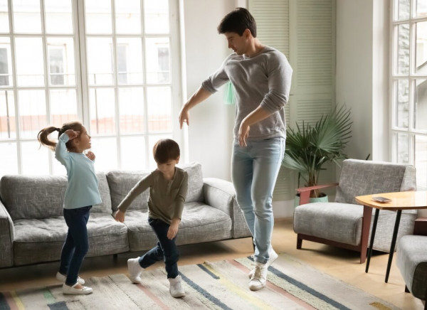 Father dancing with children at home