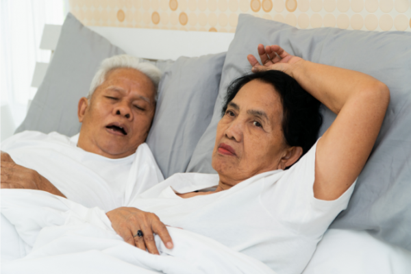 Woman awake in bed beside snoring husband