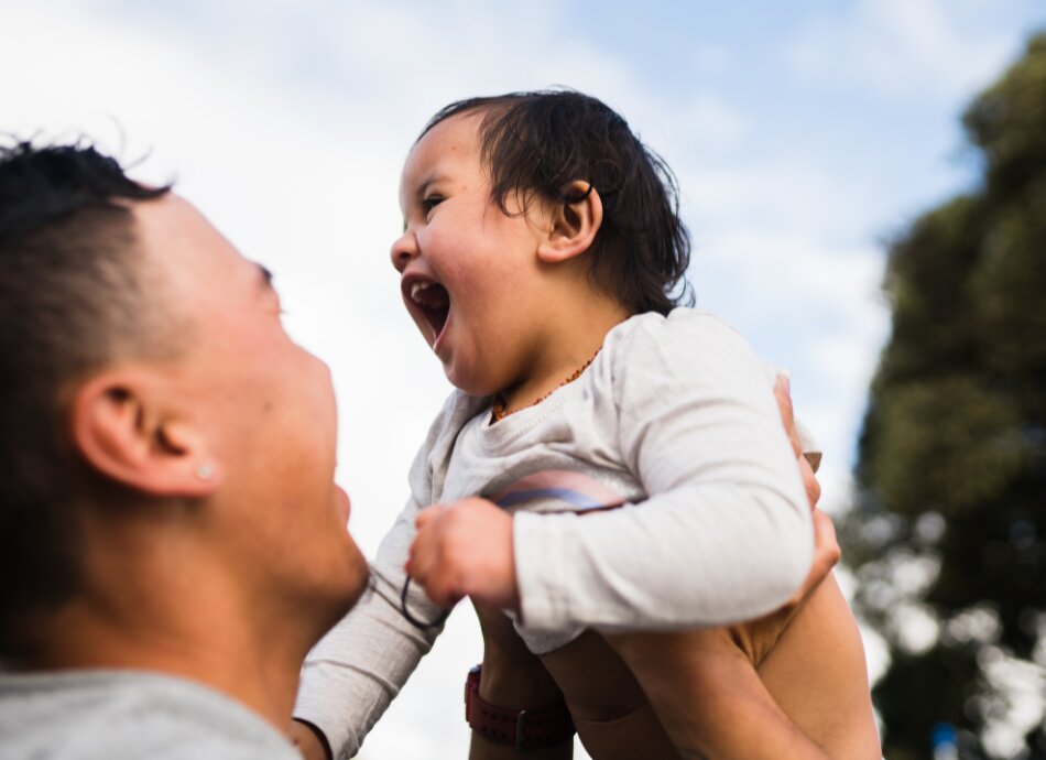 Man holds up happy laughing baby in the air