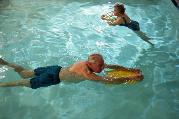 Older people swimming with kickboards in pool