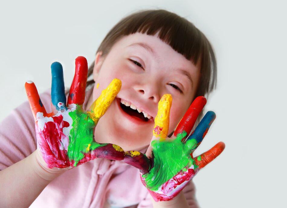 Young girl with Down syndrome and colourful paint on fingers