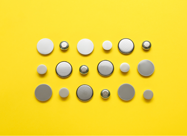 Variety of button batteries on yellow background