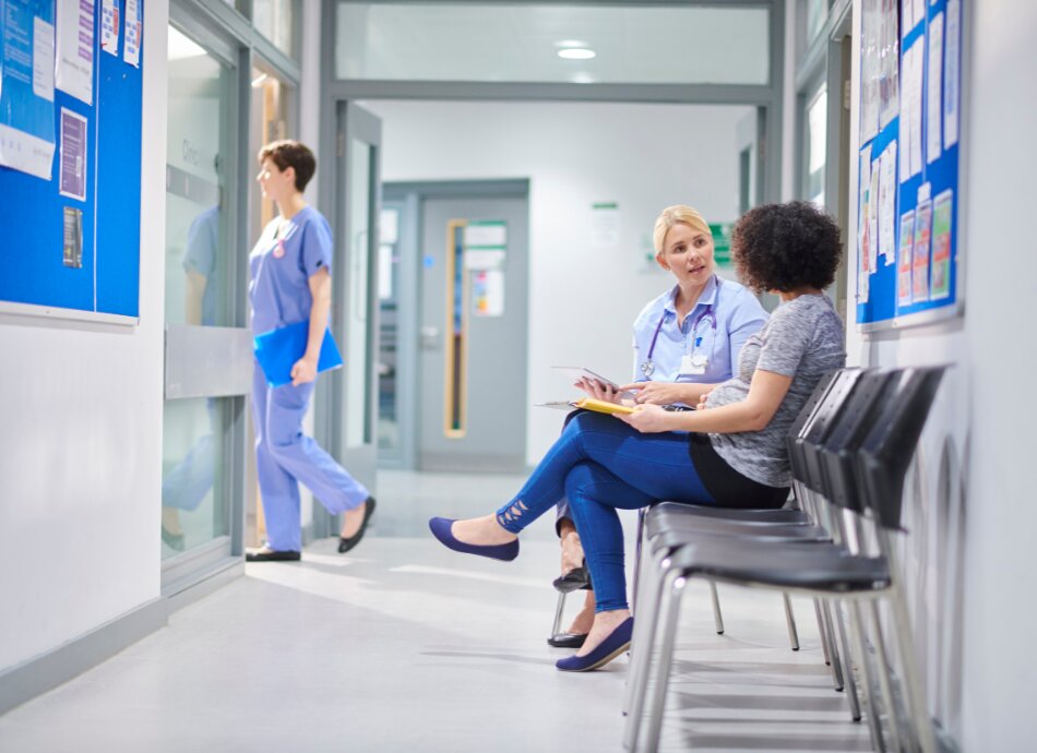 Woman sitting in hospital corridor talks to healthcare professional