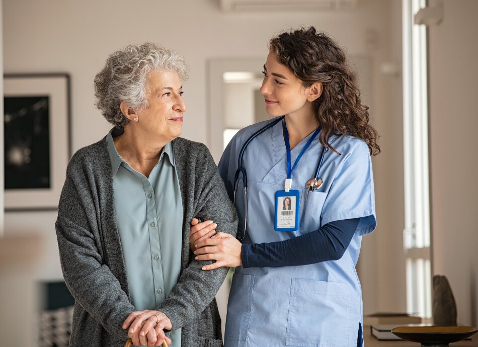 Nurse smiles at older woman with walking stick