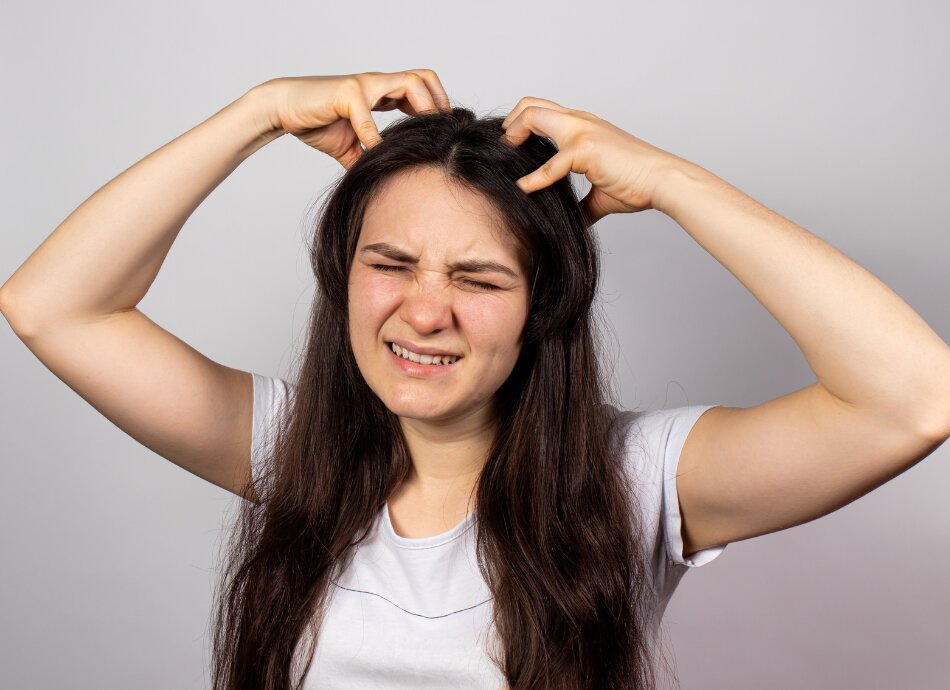 Young woman with long dark hair scratching itchy scalp