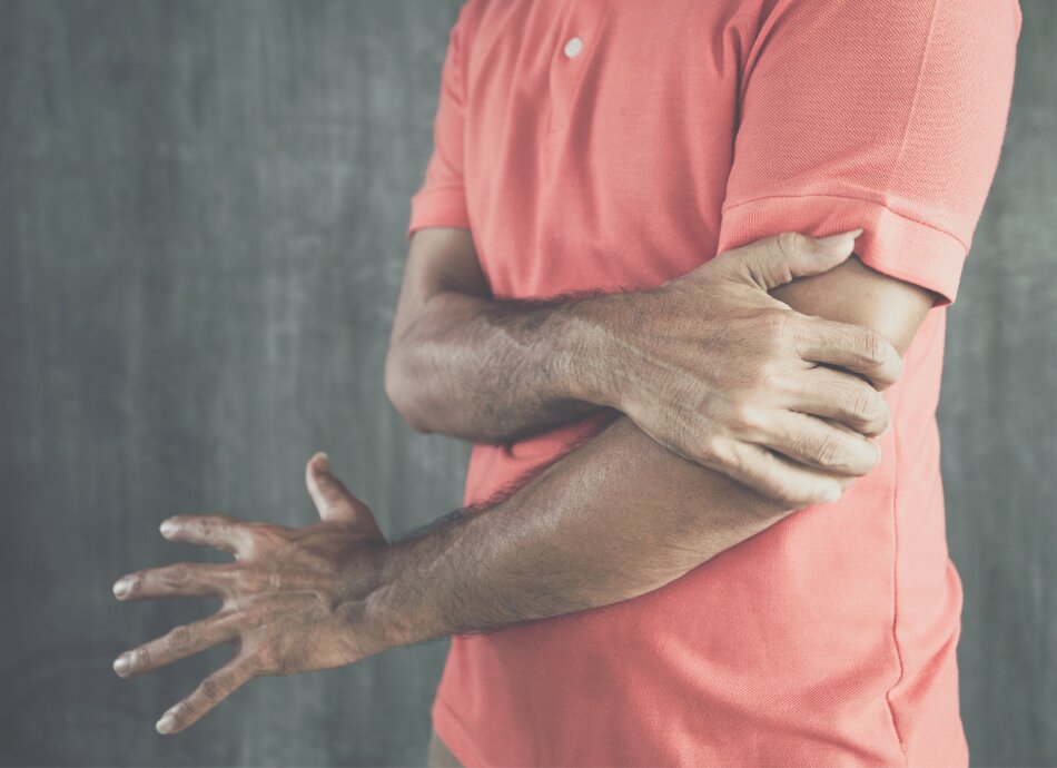 Man in orange teeshirt holds painful elbow