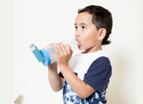 Young boy using inhaler with spacer