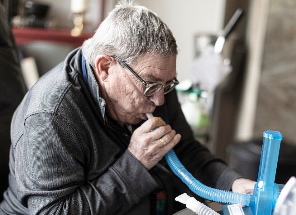 Older man blows into machine to check lung capacity