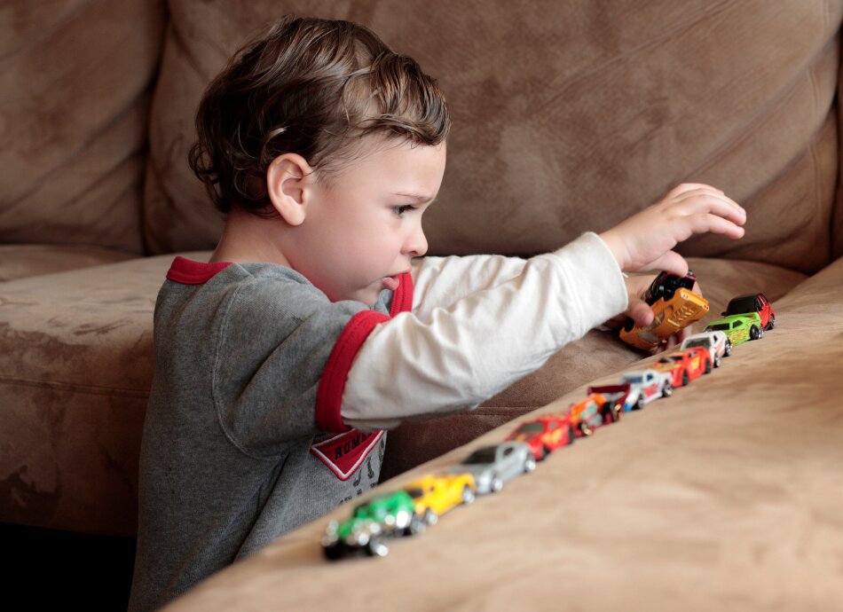 Young boy lining up small toy cars