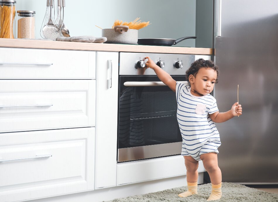 Toddler touching the oven knobs in kitchen