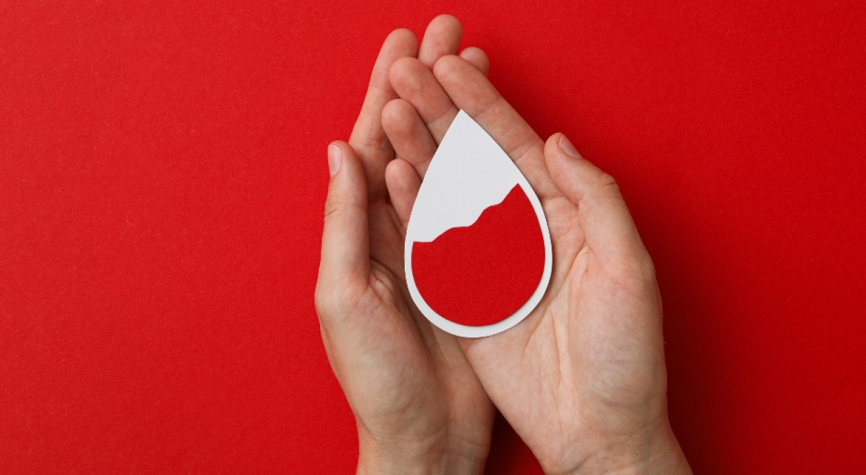 Hands holding image of drop of blood 