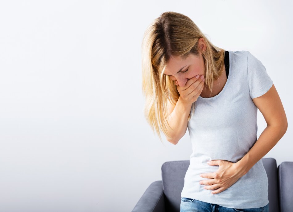 Young woman holds her tummy and feels nausea