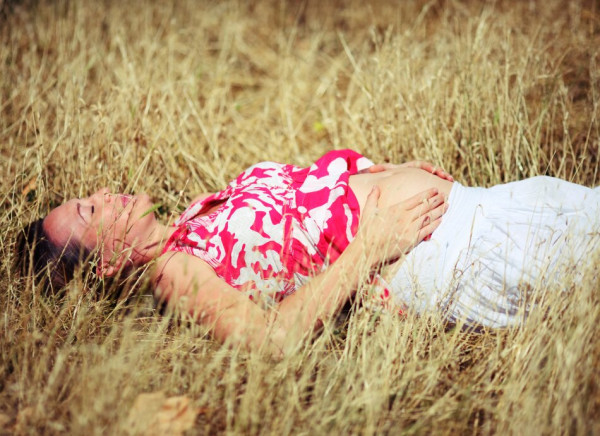 Pregnant woman lying in field sunning her stomach