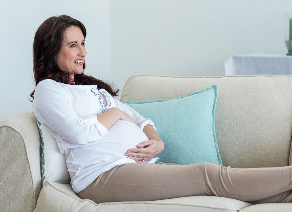 Pregnant woman resting on couch canva 950x690