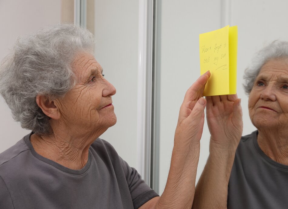 Older woman using sticky note as memory aid