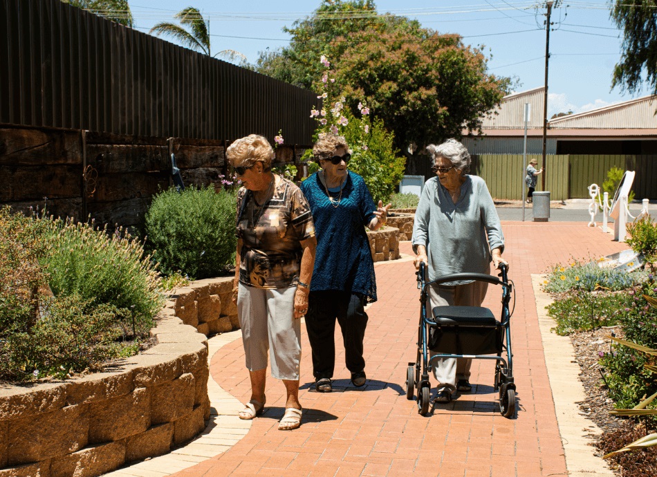 Older women walking outside, one with walker