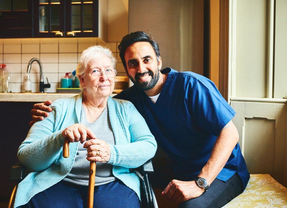 Senior woman in kitchen with carer 