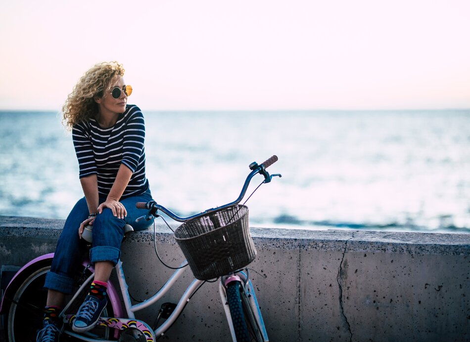 Midaged woman with bike sits on the sea wall