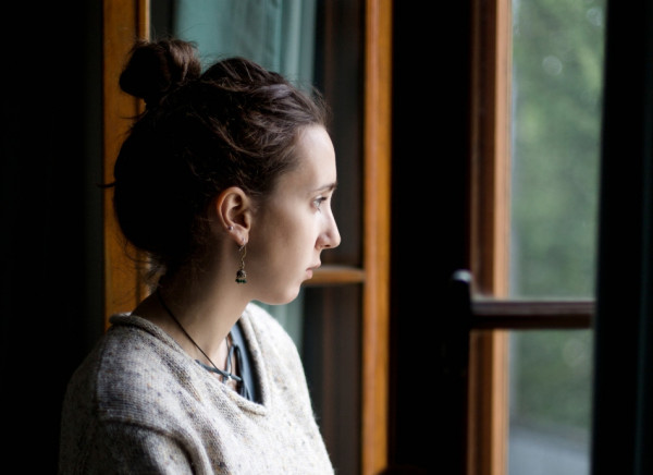 Worried young woman looks out the window
