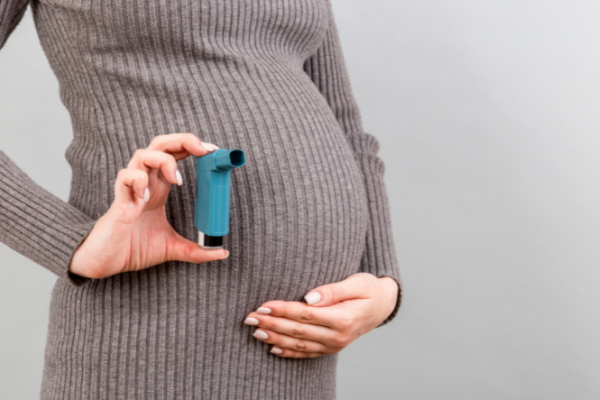 Pregnant woman holding asthma inhaler