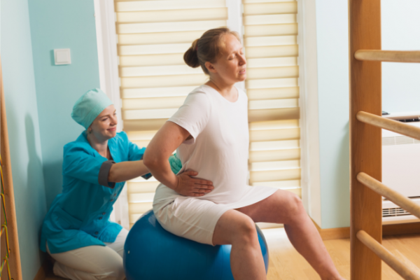 Woman in labour sitting on Swiss ball gets back massage