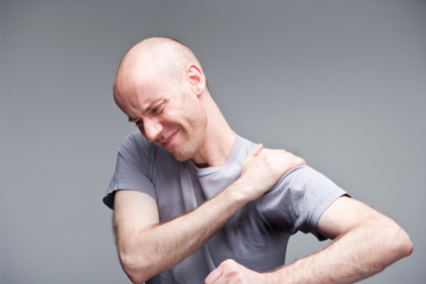 Man grimacing and holding painful shoulder