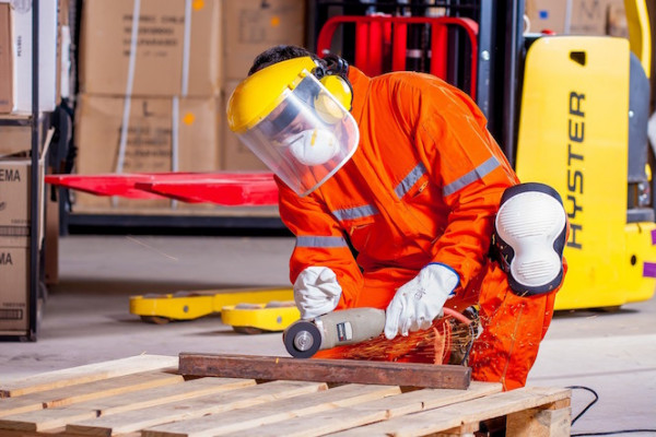 Man in safety clothing cutting steel with power tool