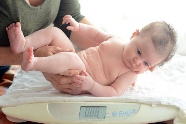 Baby being weighed on scale by nurse