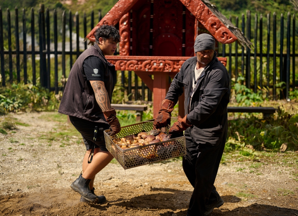 Hangi foods being carried by 2 men