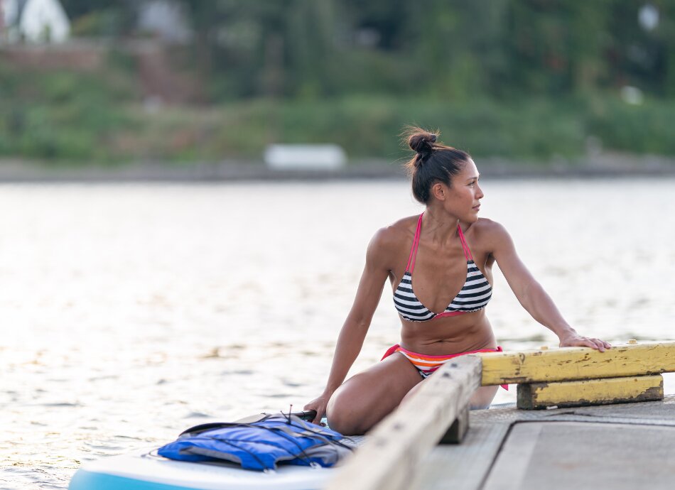 Wahine wearing striped bikini on paddle board at beach